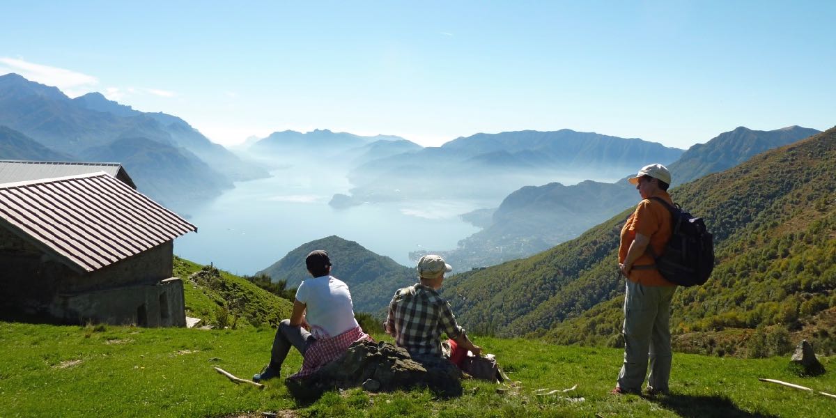 Wanderfrauen-geniessen-den-Ausblick-ueber-die-Berge-am-ComerSee-in-Italien-bei-Wanderreise-im-Fruehling